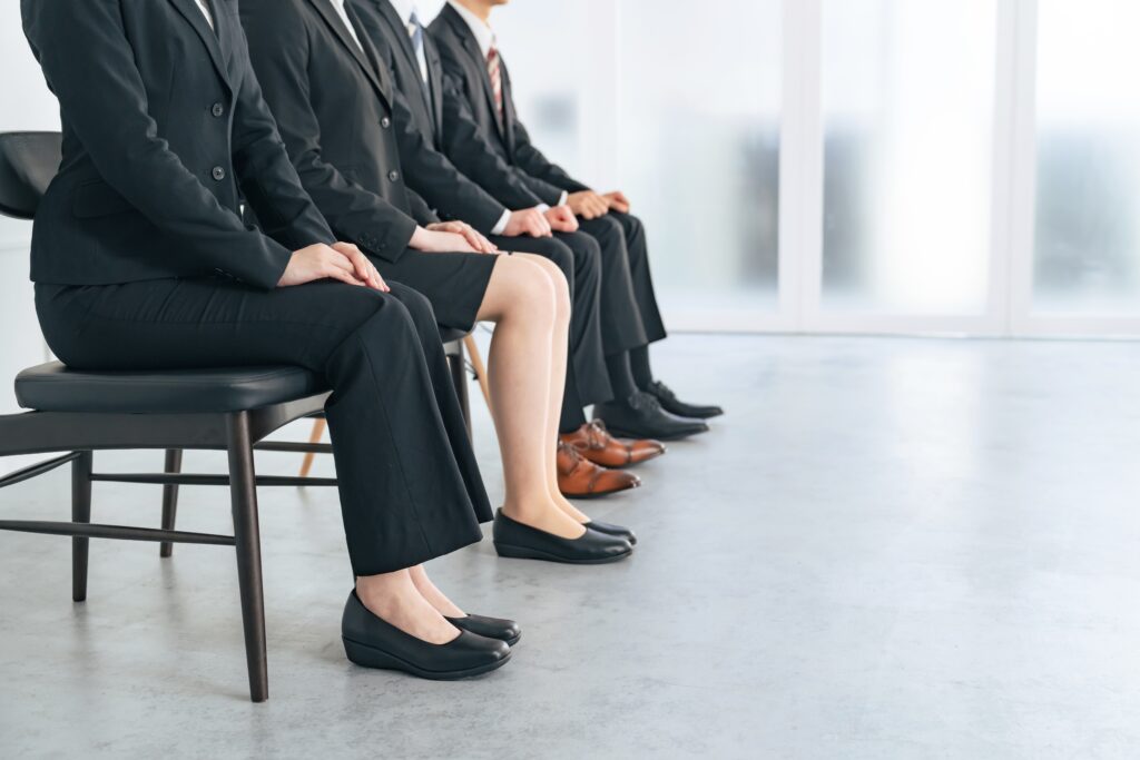 A line of job seekers sitting while waiting to be called in for a job interview