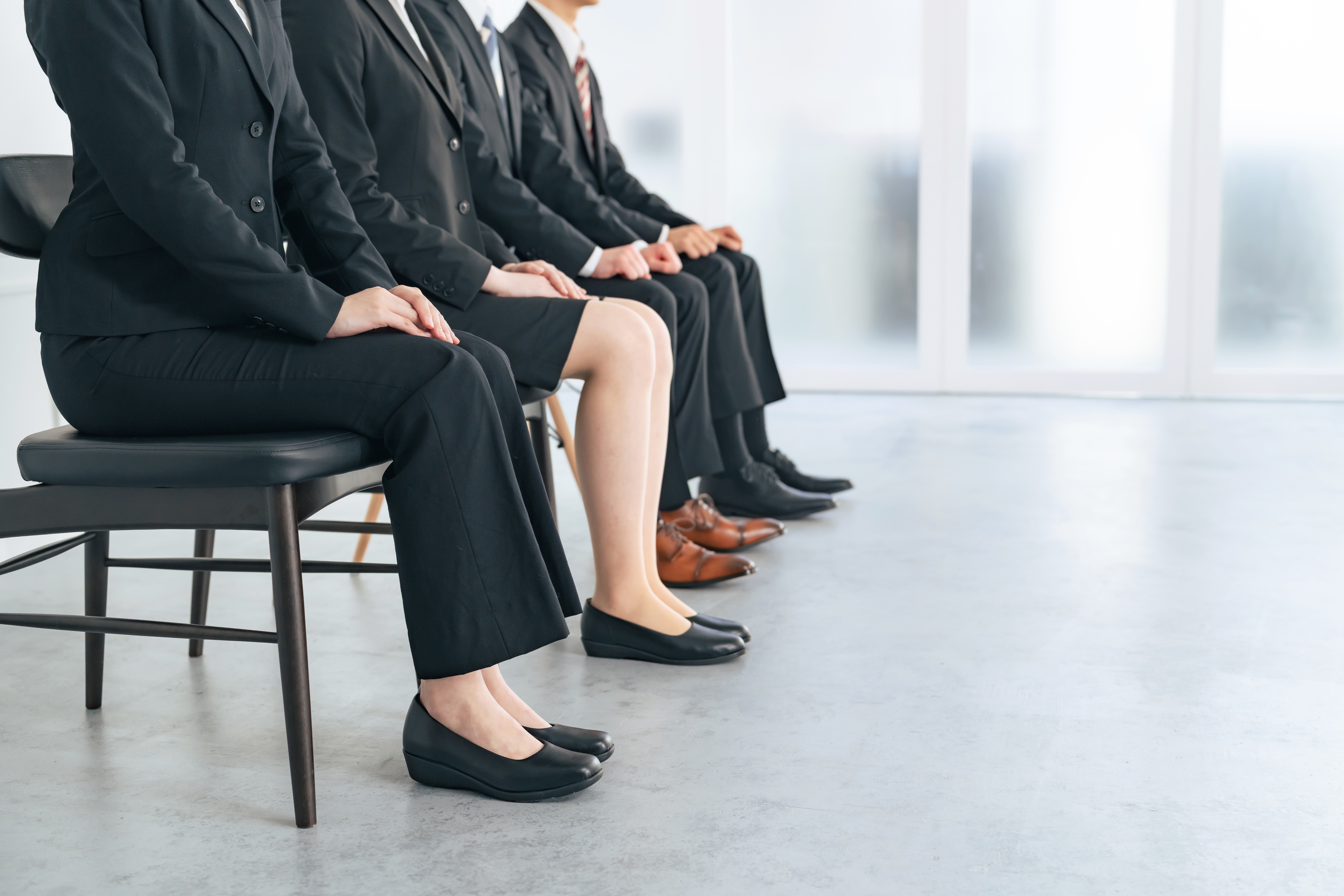 A line of job seekers sitting while waiting to be called in for a job interview