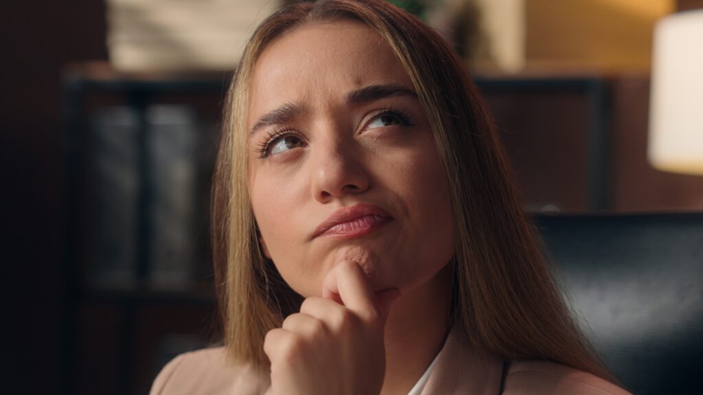 A woman resting her chin on her hand while thinking if Beymark Inc is a Scam