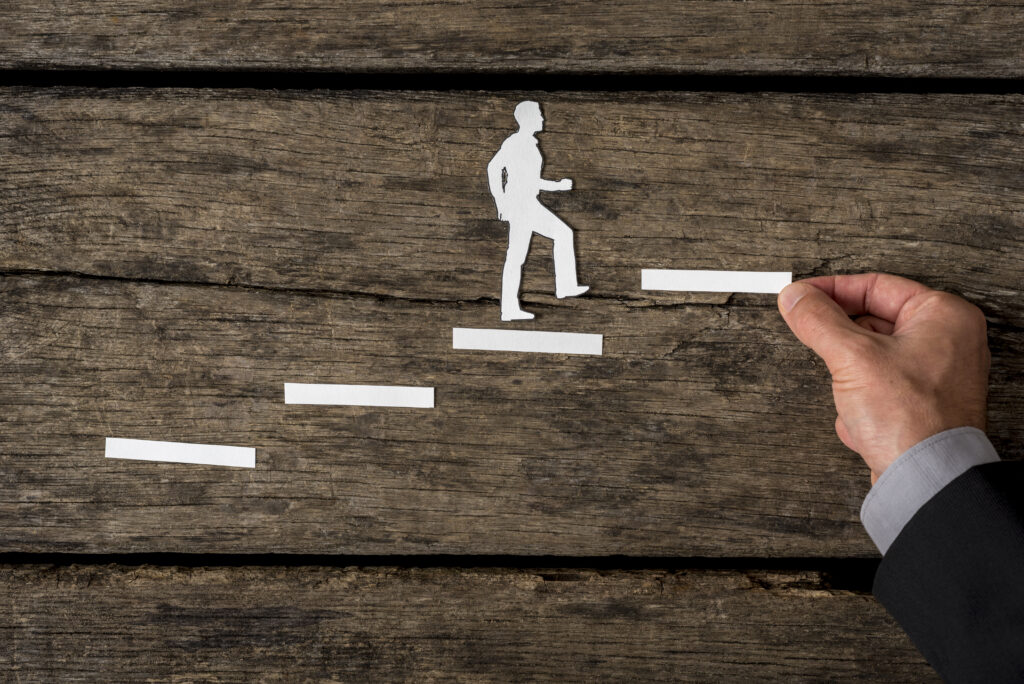 A silhouette of a professional stepping upward across a career track.