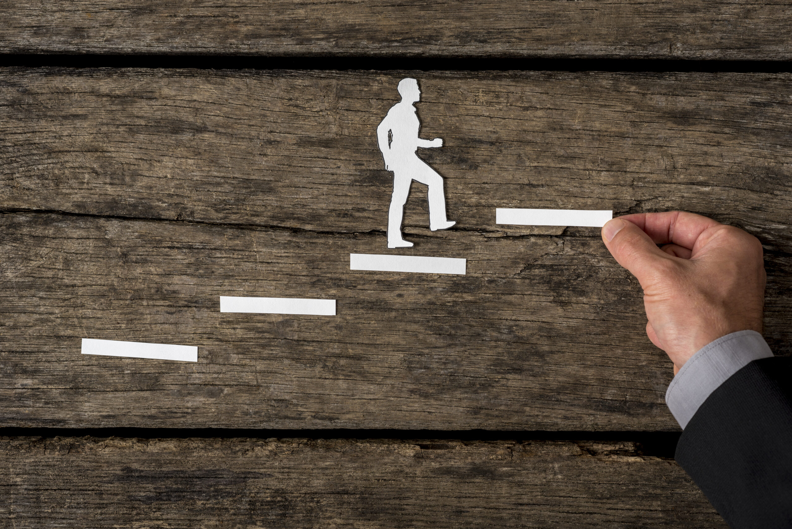 A silhouette of a professional stepping upward across a career track.