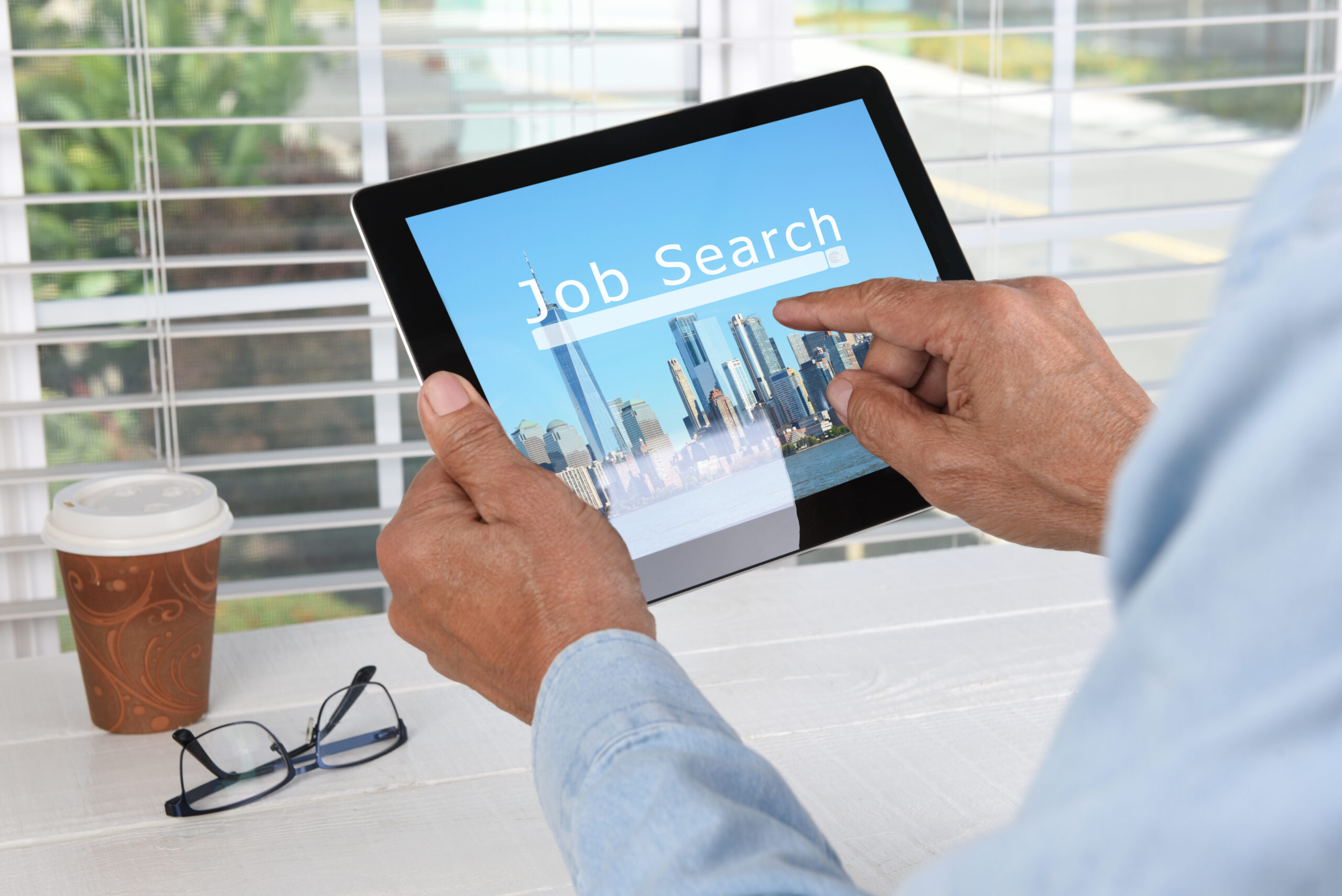 A professional searching for marketing jobs using a tablet.